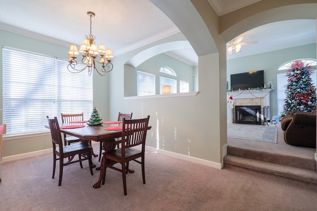 carpeted dining area with a fireplace, ceiling fan with notable chandelier, and ornamental molding