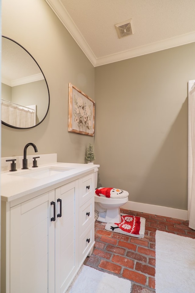 bathroom with toilet, vanity, and ornamental molding