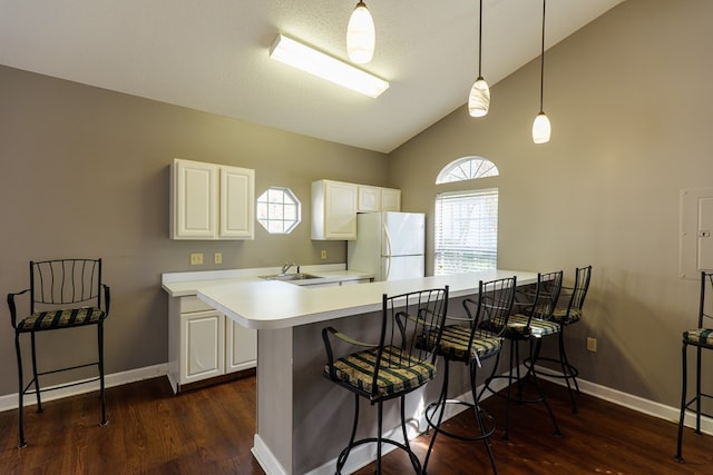 kitchen with white cabinetry, white refrigerator, kitchen peninsula, pendant lighting, and a breakfast bar