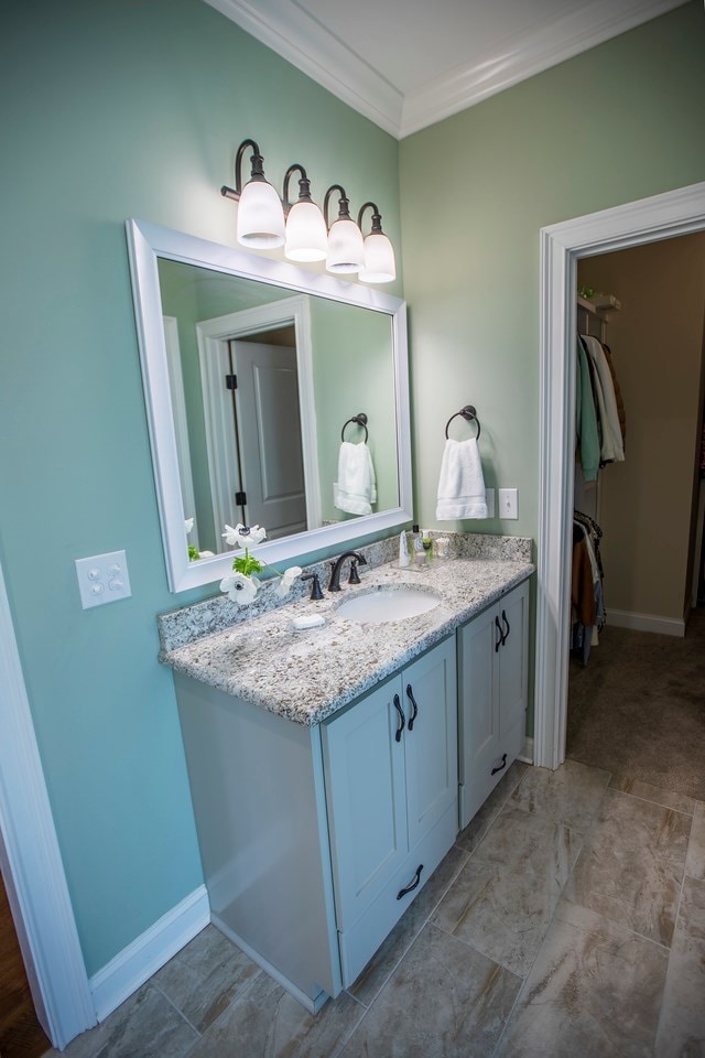 bathroom featuring baseboards, ornamental molding, and vanity