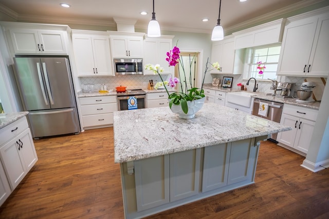 kitchen with a sink, crown molding, white cabinets, and stainless steel appliances