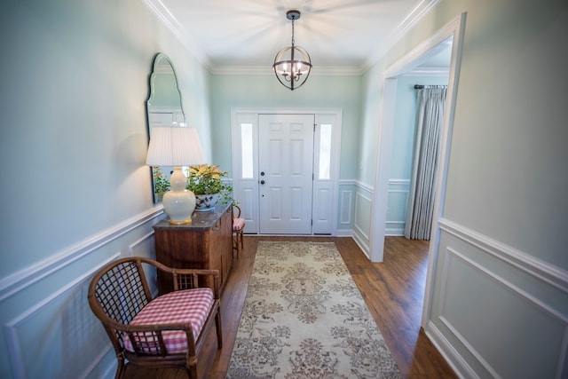 foyer entrance with a wainscoted wall, wood finished floors, crown molding, a decorative wall, and a chandelier