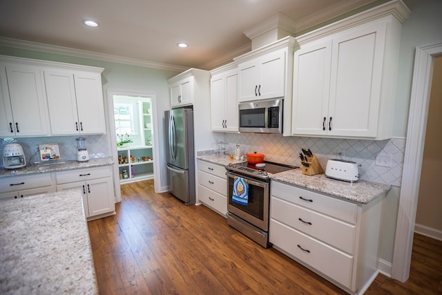 kitchen featuring appliances with stainless steel finishes, dark wood finished floors, crown molding, and white cabinets