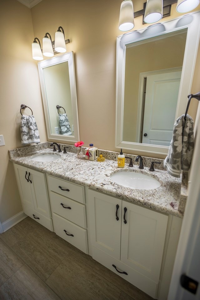 bathroom with double vanity, baseboards, and a sink