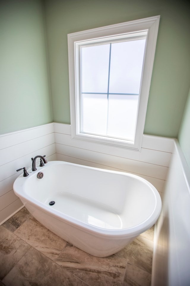 bathroom with a wainscoted wall and a tub