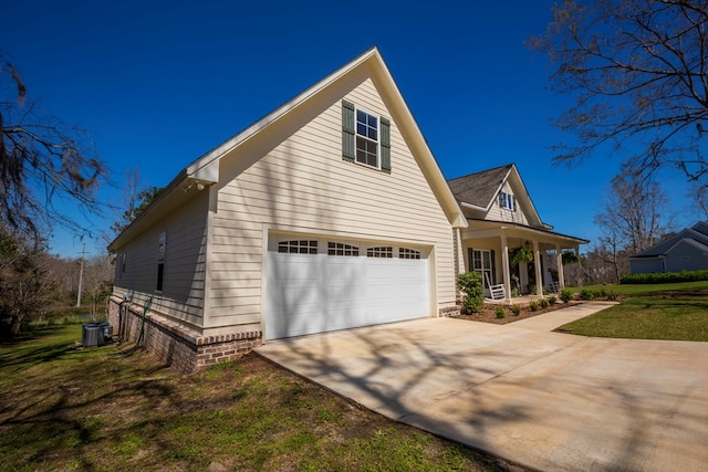 view of side of property featuring cooling unit, a porch, a yard, concrete driveway, and a garage