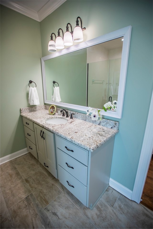 bathroom featuring vanity, crown molding, and baseboards