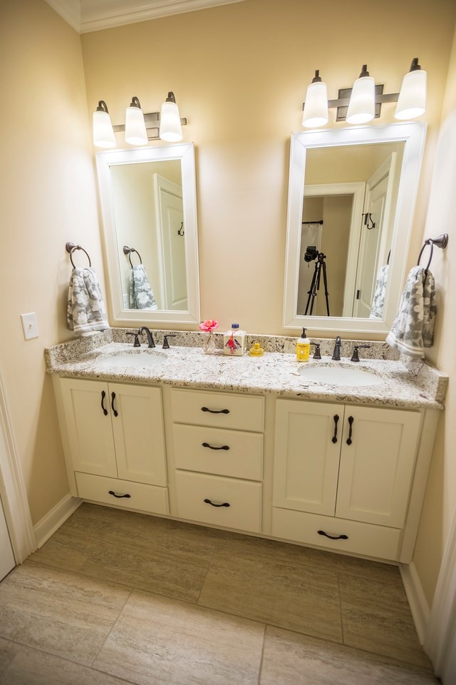 bathroom with double vanity, baseboards, and a sink