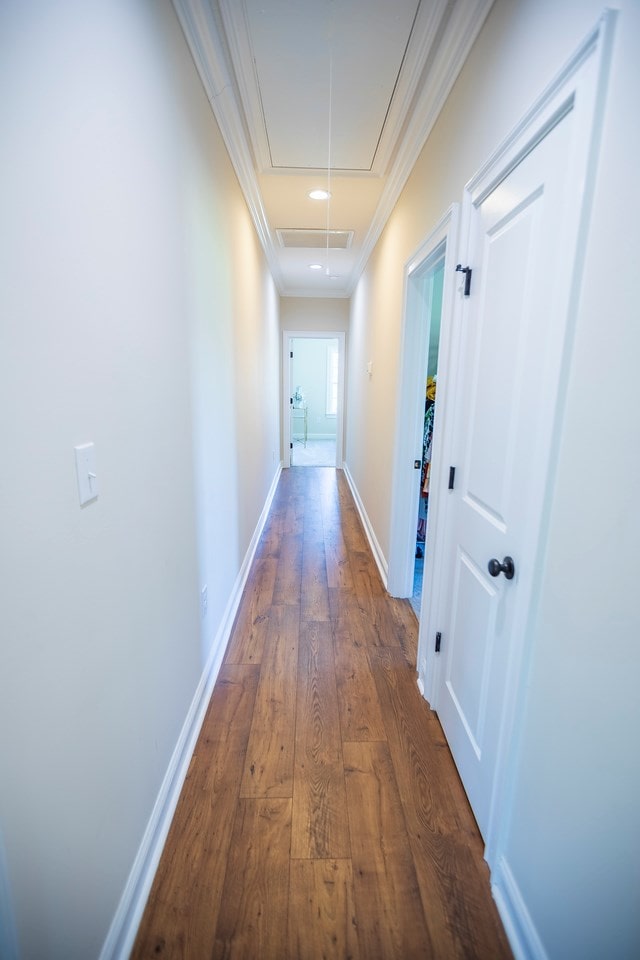 corridor featuring baseboards, dark wood finished floors, attic access, recessed lighting, and ornamental molding