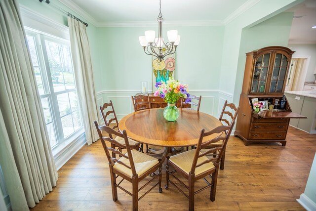 dining area featuring an inviting chandelier, plenty of natural light, light wood-style floors, and ornamental molding