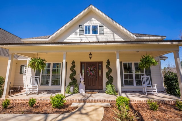 property entrance featuring covered porch and roof with shingles