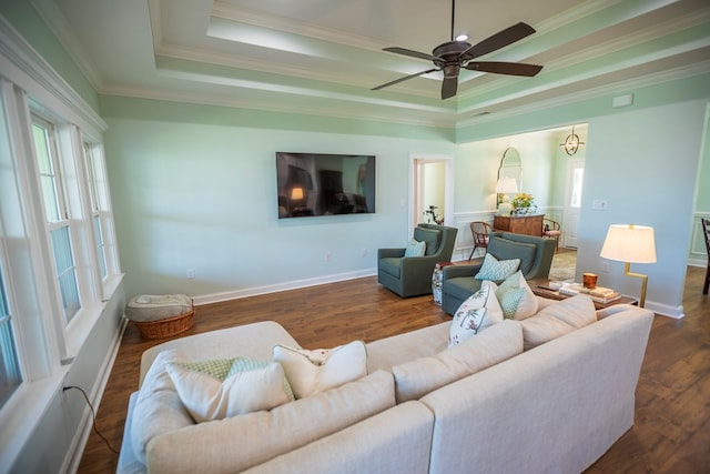 living room with a tray ceiling, baseboards, wood finished floors, and crown molding