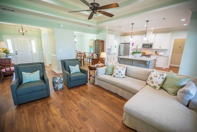 living room with visible vents, wood finished floors, and crown molding