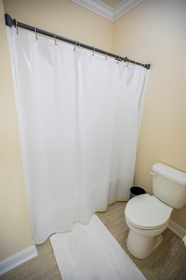 full bath with baseboards, wood finished floors, toilet, and ornamental molding