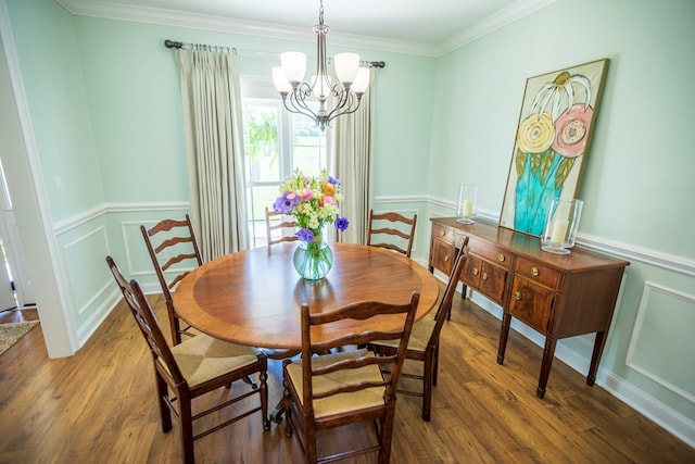 dining area featuring a wainscoted wall, ornamental molding, an inviting chandelier, wood finished floors, and a decorative wall