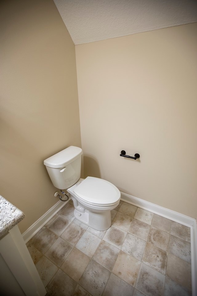 half bathroom with toilet and baseboards