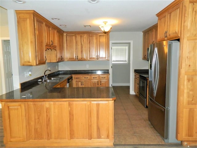 kitchen featuring stainless steel fridge, range with electric cooktop, a sink, dark countertops, and a peninsula