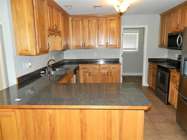 kitchen featuring light tile patterned floors, visible vents, a sink, a peninsula, and stainless steel appliances