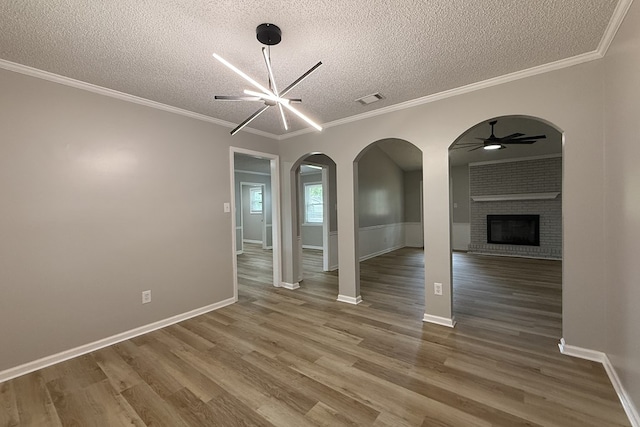 4604 Pinebrook Dr, Lake Park, GA 31636 - unfurnished living room featuring a textured ceiling, a ceiling fan, a fireplace, wood finished floors, and arched walkways