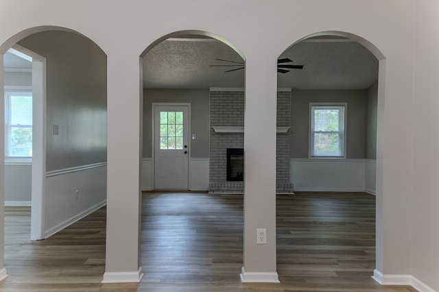 4604 Pinebrook Dr, Lake Park, GA 31636 - unfurnished living room featuring a ceiling fan, wood finished floors, a brick fireplace, a textured ceiling, and a wainscoted wall