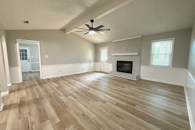 4604 Pinebrook Dr, Lake Park, GA 31636 - unfurnished living room featuring a textured ceiling, ceiling fan, wainscoting, a brick fireplace, and light wood finished floors