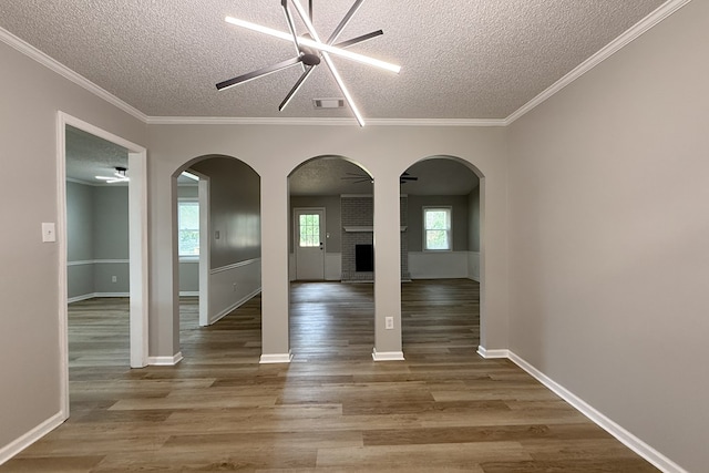 4604 Pinebrook Dr, Lake Park, GA 31636 - spare room featuring a textured ceiling, wood finished floors, healthy amount of natural light, a fireplace, and arched walkways