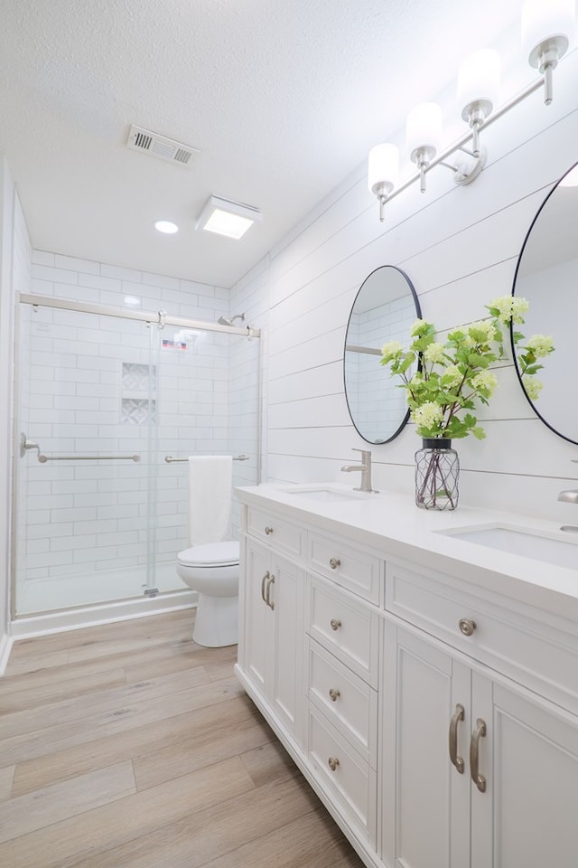 bathroom with hardwood / wood-style flooring, vanity, an enclosed shower, toilet, and a textured ceiling