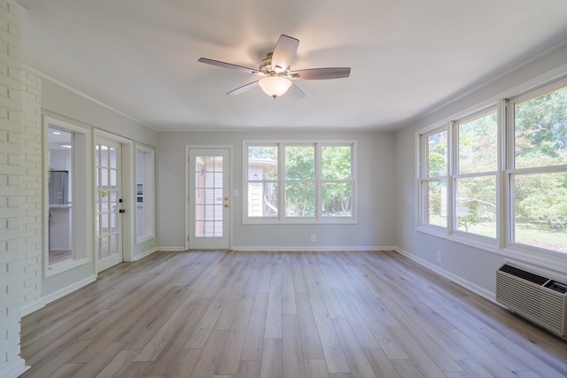 unfurnished sunroom featuring ceiling fan and a wall mounted air conditioner