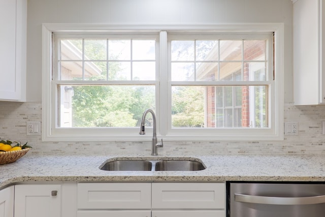 kitchen with white cabinetry, stainless steel dishwasher, light stone countertops, and sink