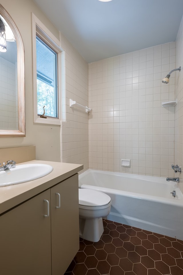 full bathroom featuring tile patterned flooring, vanity, tiled shower / bath combo, and toilet