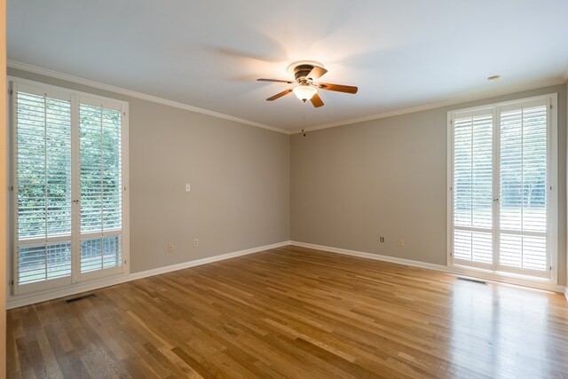 empty room with a wealth of natural light, hardwood / wood-style floors, ceiling fan, and ornamental molding