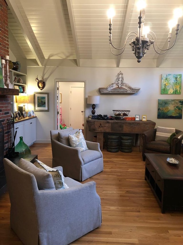 living room with vaulted ceiling with beams, a brick fireplace, wood-type flooring, and a notable chandelier