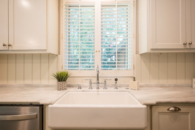 kitchen featuring plenty of natural light, white cabinets, stainless steel dishwasher, and sink