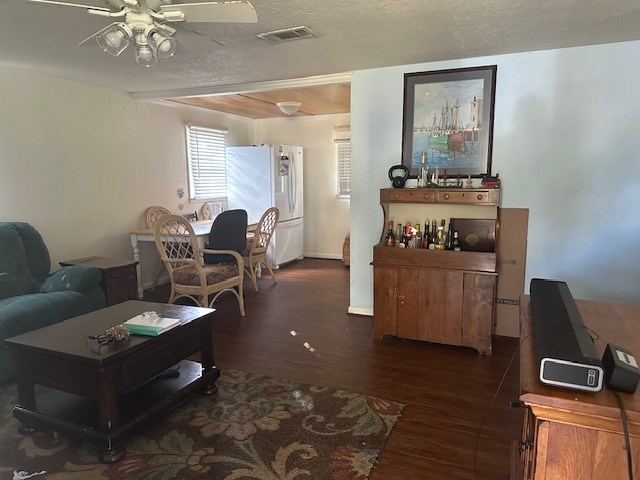 living room with ceiling fan, dark hardwood / wood-style flooring, and a textured ceiling