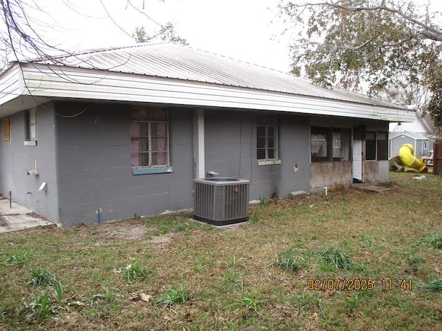 rear view of property with central AC and a lawn