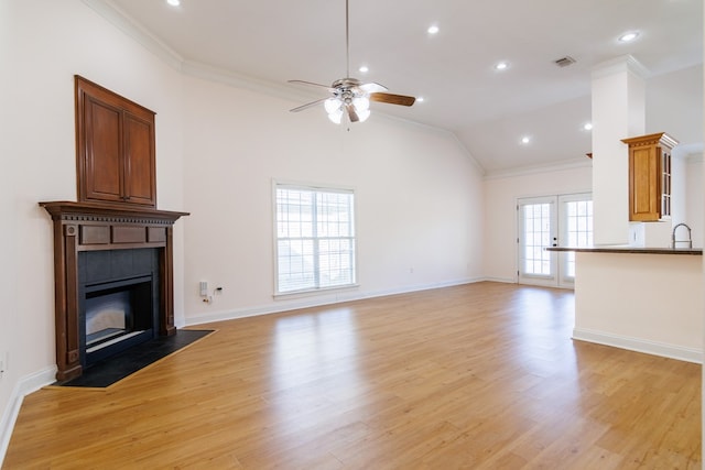 unfurnished living room featuring light wood-style floors, a fireplace with flush hearth, a ceiling fan, and crown molding