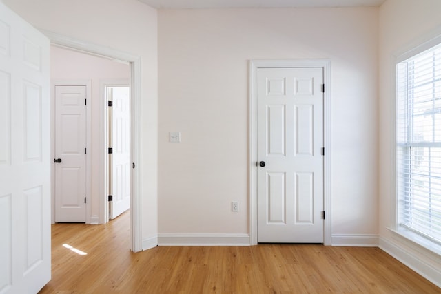 unfurnished bedroom with light wood-style flooring and baseboards