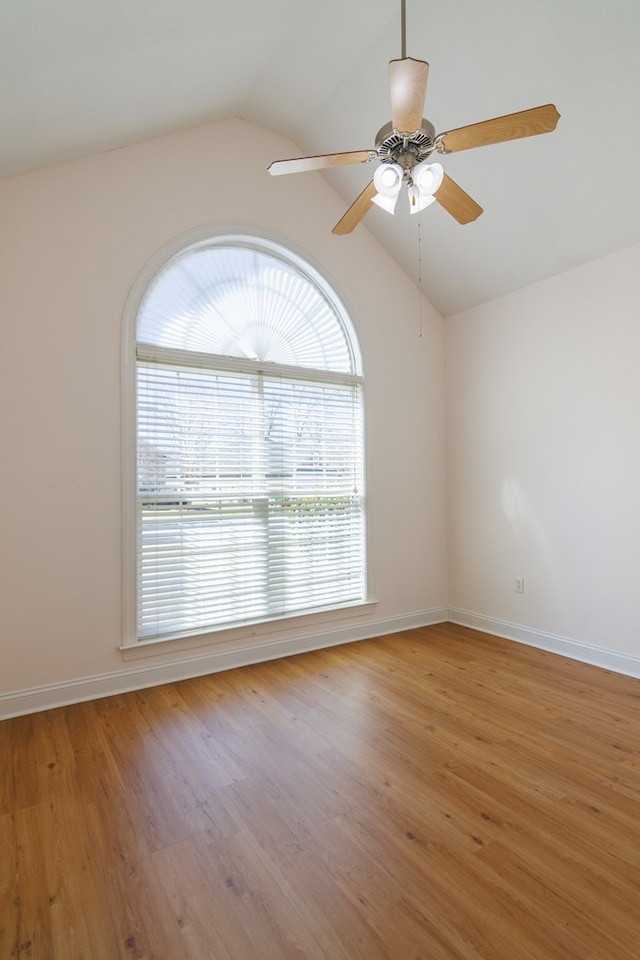 empty room with light wood-type flooring, baseboards, a ceiling fan, and lofted ceiling