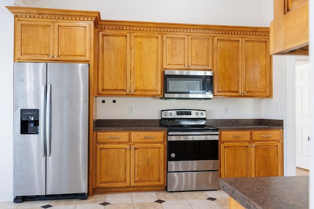 kitchen featuring stainless steel appliances, brown cabinetry, and dark countertops