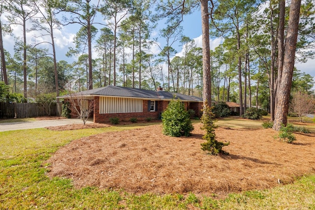 view of front of property with brick siding, concrete driveway, a chimney, fence, and a front yard