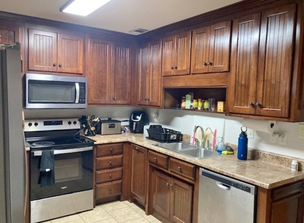 kitchen with light tile patterned flooring, appliances with stainless steel finishes, and sink