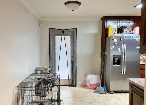 kitchen with dark brown cabinetry, crown molding, and stainless steel refrigerator with ice dispenser