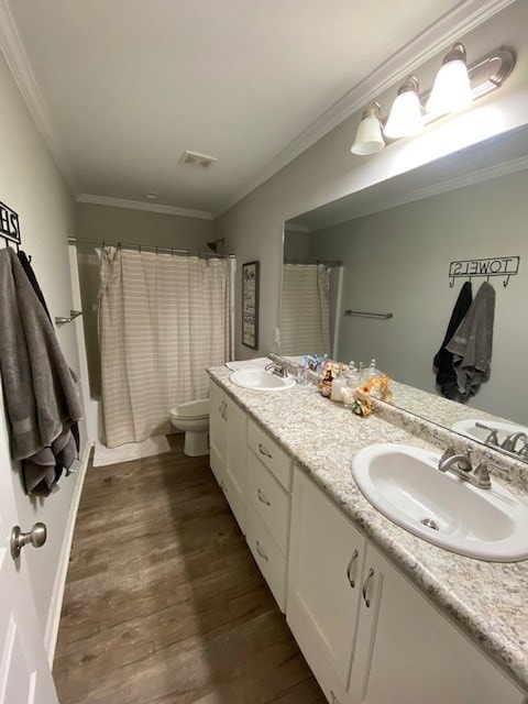 bathroom featuring toilet, wood finished floors, a sink, visible vents, and ornamental molding