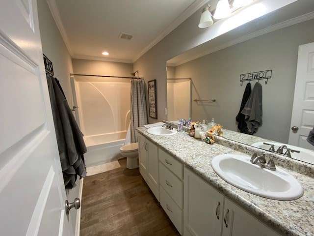 bathroom with wood finished floors, a sink, toilet, and crown molding