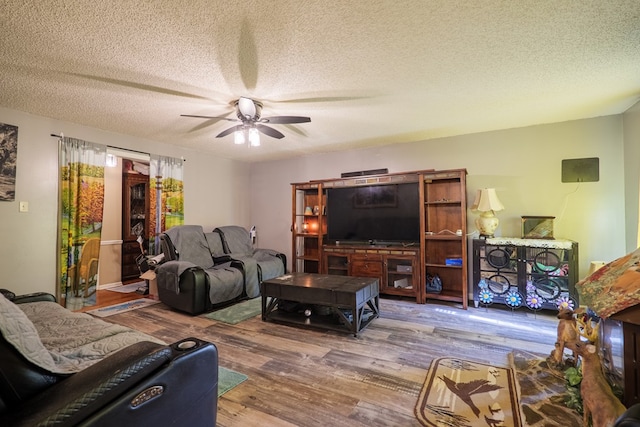 living room featuring ceiling fan, wood-type flooring, and a textured ceiling