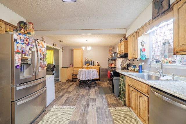 kitchen with sink, hardwood / wood-style floors, stainless steel appliances, a textured ceiling, and decorative light fixtures