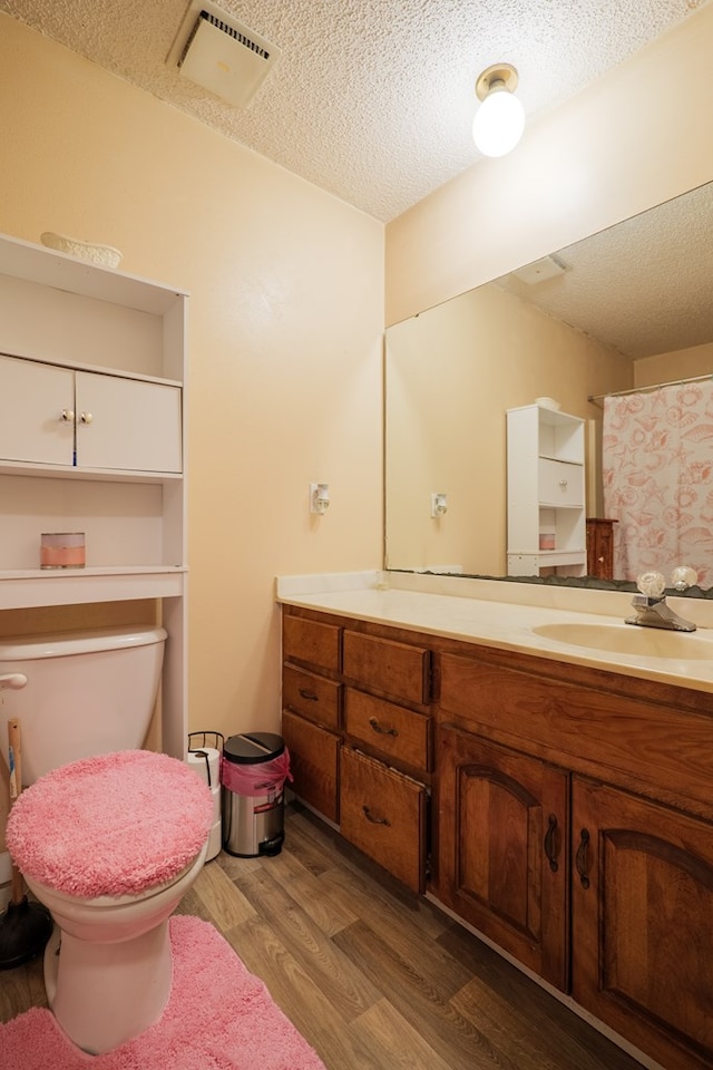 bathroom featuring hardwood / wood-style flooring, vanity, toilet, and a textured ceiling