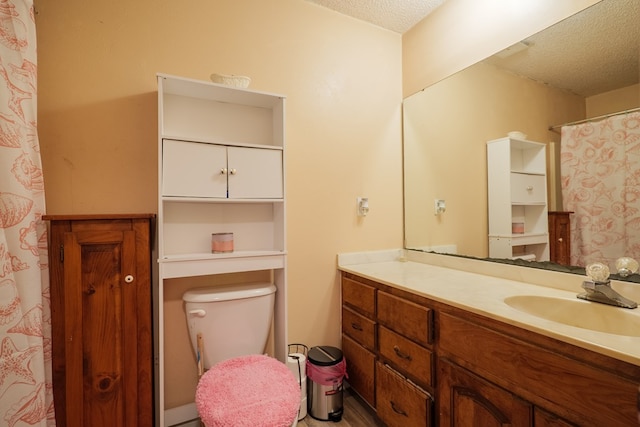 bathroom featuring vanity, a textured ceiling, and toilet