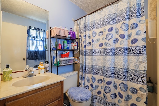 bathroom with a shower with curtain, vanity, a textured ceiling, and toilet