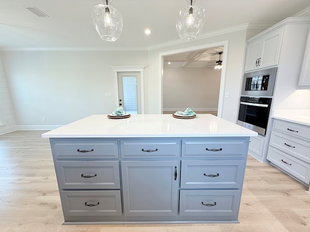 4965 Hatfield Cir, Hahira, GA 31632 - kitchen with appliances with stainless steel finishes, a kitchen island, pendant lighting, a ceiling fan, and light wood finished floors